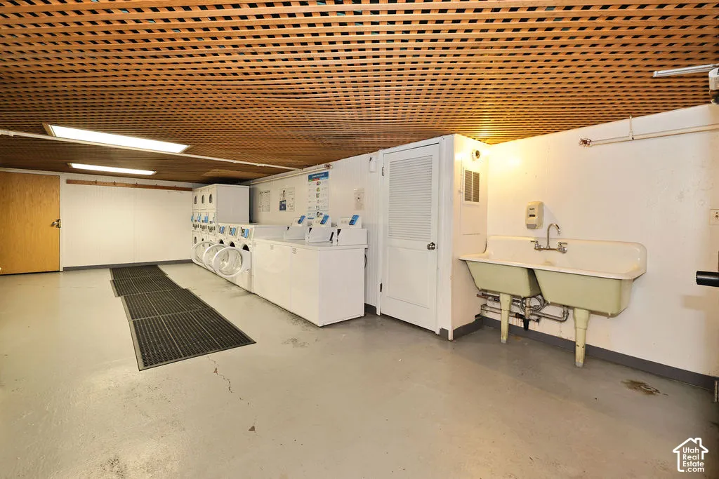 Utility space featuring a wood-slat ceiling, integrated laundry appliances, dual-basin utility sink, and recessed lighting