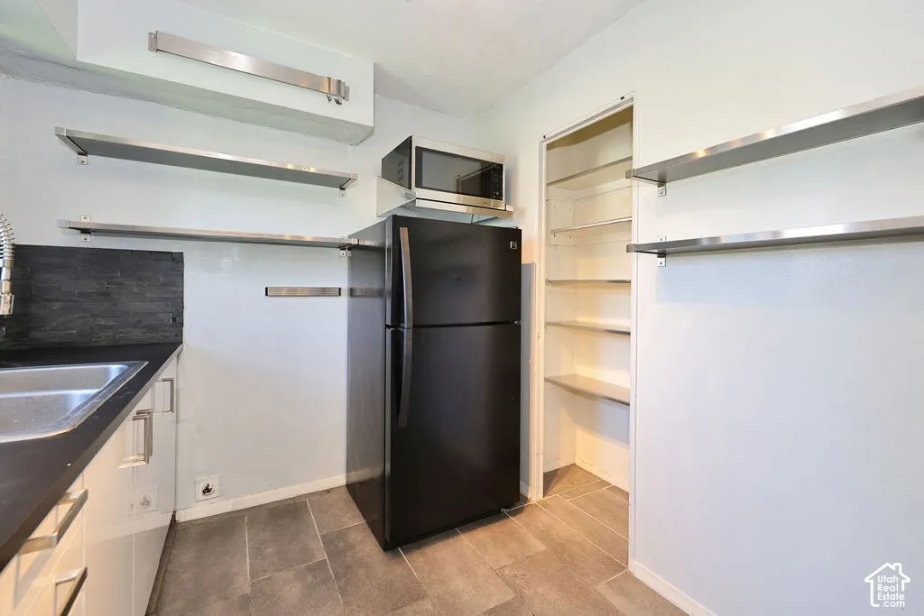 Kitchen featuring stone-finish counters, stainless steel open shelving, tile flooring, a walk-in pantry, and a built-in microwave