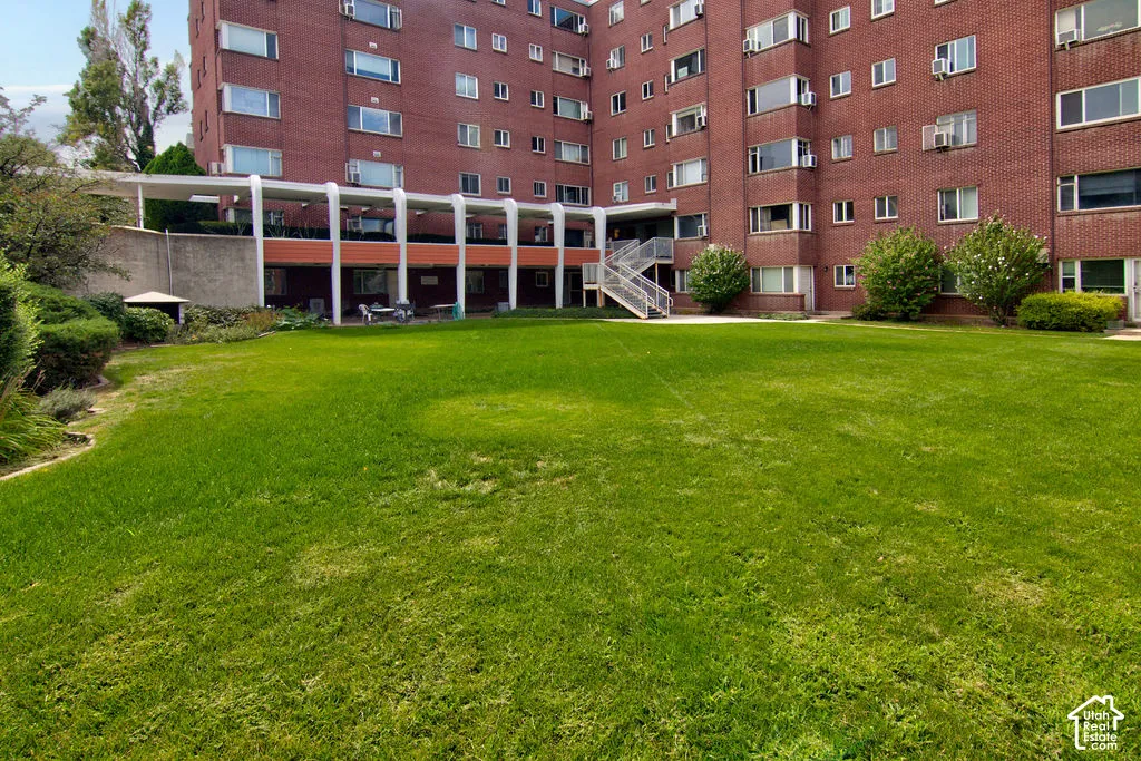 Expansive lawn area featuring a multi-story brick facade, concrete colonnade, and metal stair assembly