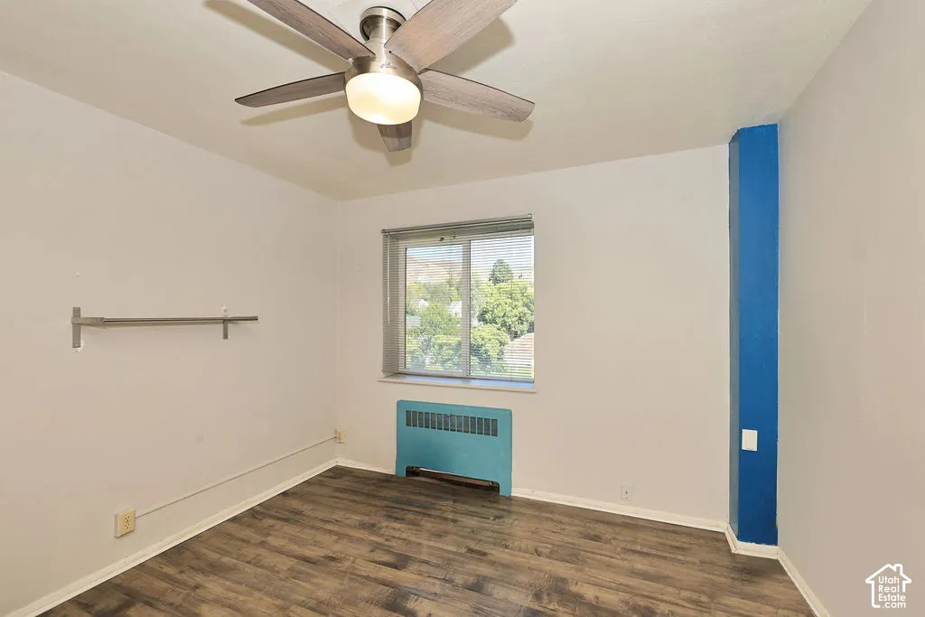 Room featuring wood-finish flooring, a ceiling fan with integrated lighting, a sliding window, and a wall-mounted metal rack