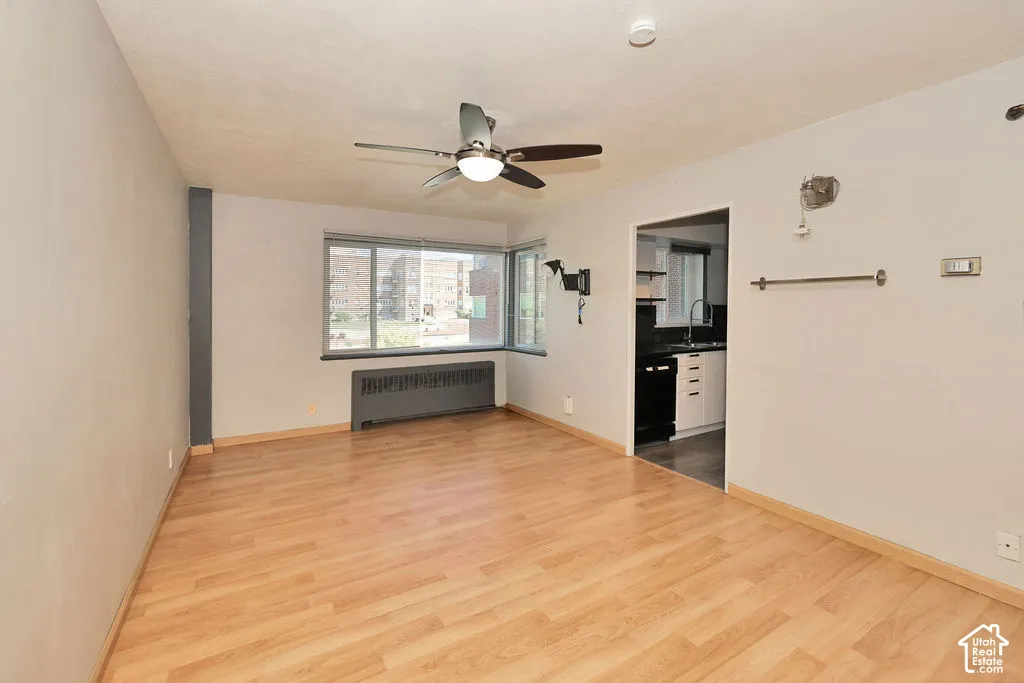 Living area featuring wood-finish flooring, a ceiling fan with integrated lighting, and large windows