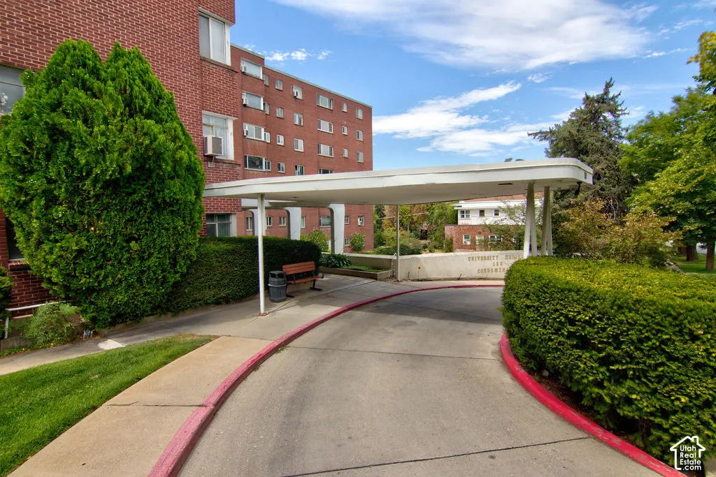 Red brick mid-rise exterior featuring a concrete porte-cochere, circular driveway, and manicured landscaping