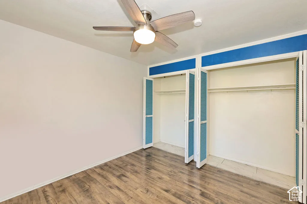Wood-finish flooring, brushed nickel ceiling fan with integrated lighting, and dual closets featuring louvered doors