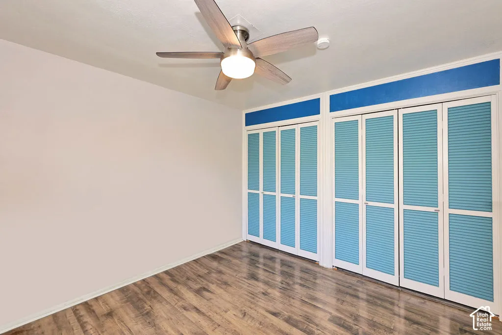 Wood-finish flooring, ceiling fan with integrated lighting, and dual louvered-style closet doors