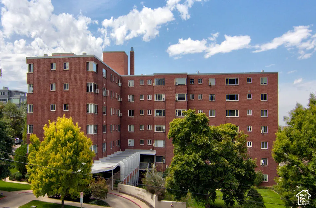 Multi-story brick exterior featuring a flat roofline, curved covered entryway, and established mature trees