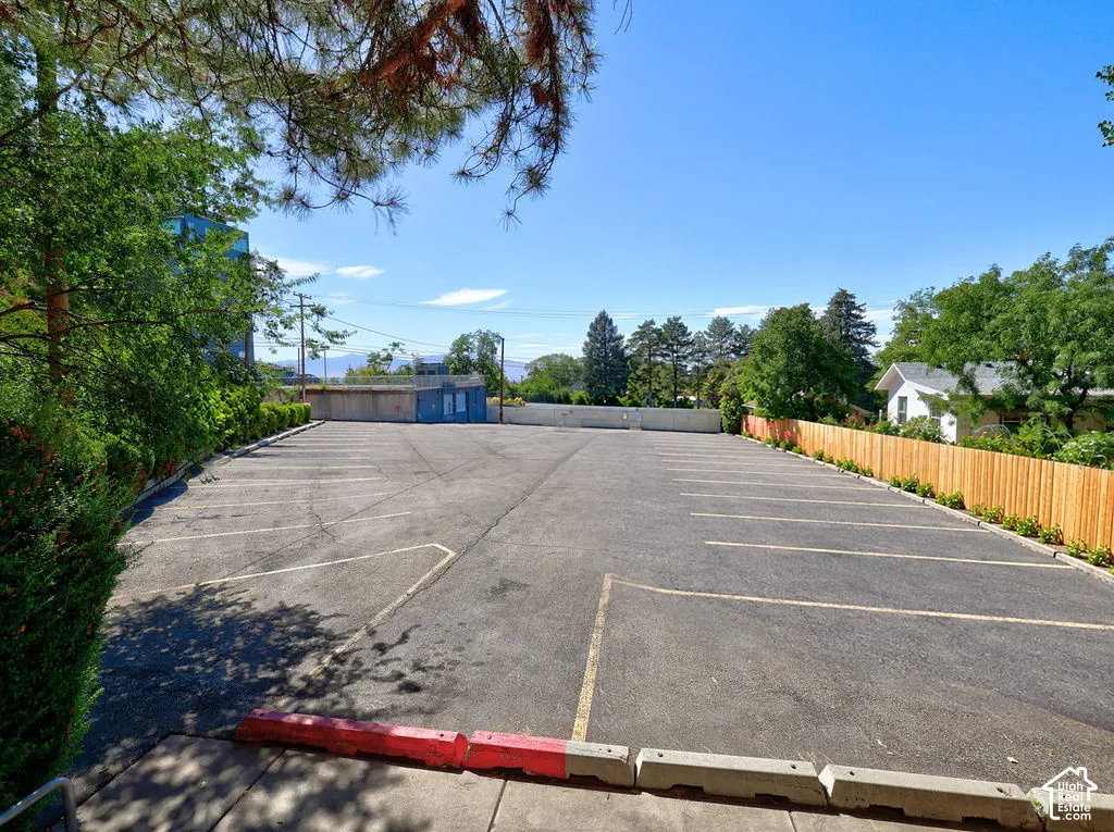 Paved parking lot featuring marked parking stalls, concrete wheel stops, and perimeter wood fencing