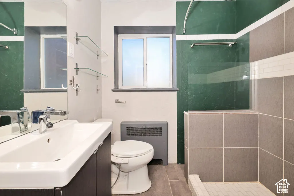 Bathroom featuring a white ceramic sink with a chrome faucet, large rectangular wall-mounted mirror, glass shelving, and a tiled shower enclosure with a glass panel