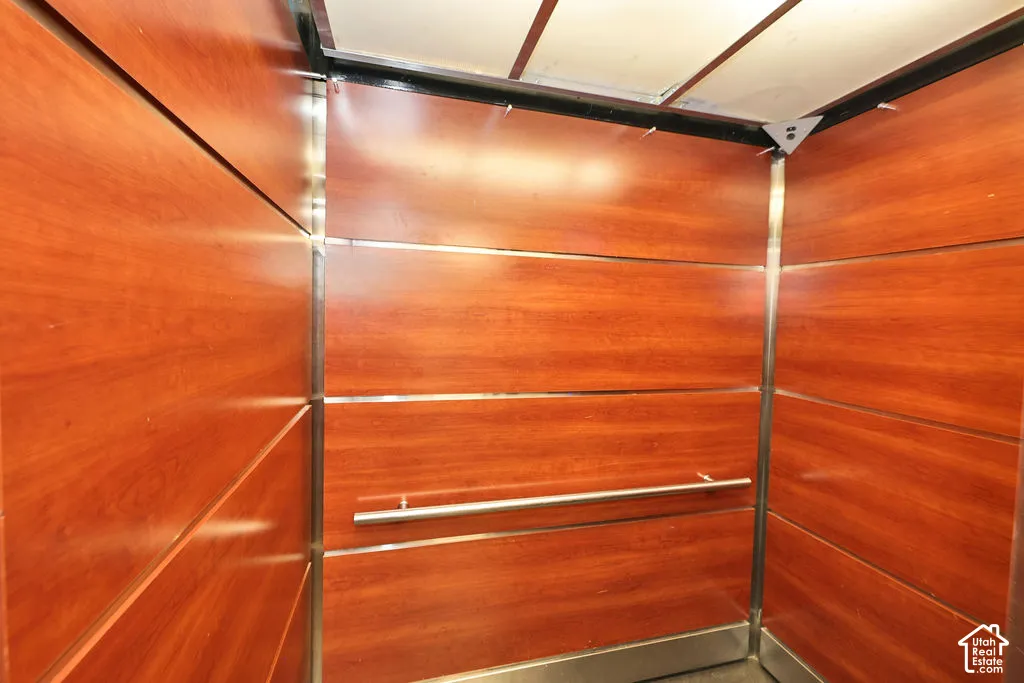 Interior elevator featuring wood-finish wall panels, metallic trim, and a horizontal stainless steel handrail