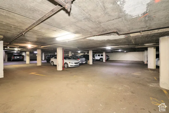 Covered parking garage featuring a concrete ceiling, support columns, and overhead lighting