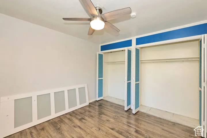 Wood-finish flooring, brushed nickel ceiling fan with integrated light fixture, dual closets with louvered folding doors, and built-in shelving