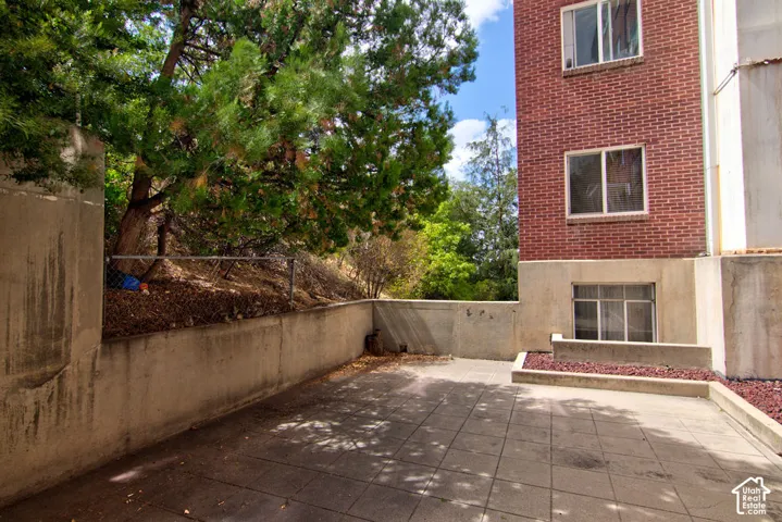 Private paved patio featuring concrete retaining walls and mature trees