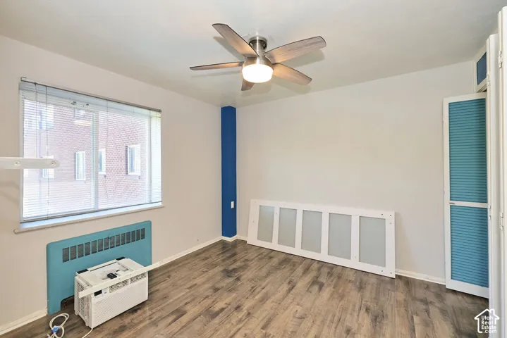 Wood-finish flooring, ceiling fan with integrated lighting, window with horizontal blinds, and louvered closet doors