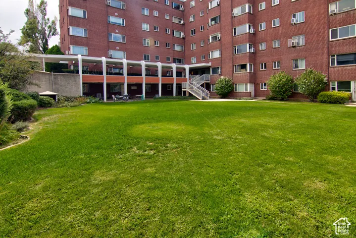 Expansive grounds featuring a manicured lawn, red brick multi-story structure, sheltered exterior walkway, and metal staircase