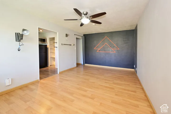 Wood-finish flooring, ceiling fan with integrated light fixture, and wall-mounted light fixtures