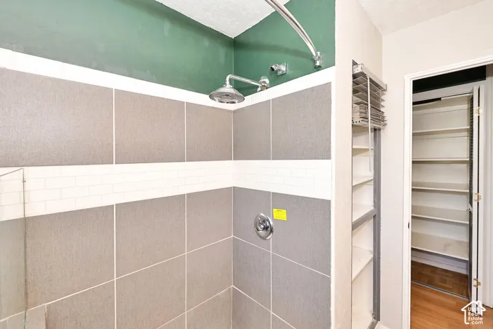 Shower enclosure featuring large-format grey tile walls with a horizontal white subway tile inlay, chrome shower fixture, and built-in shelving
