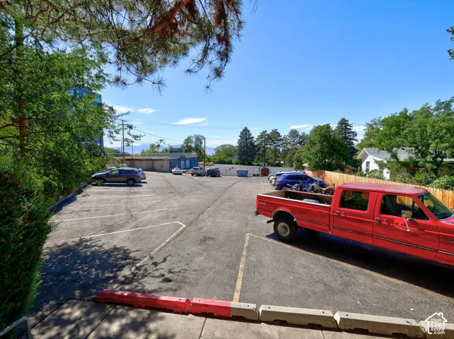 Asphalt-paved parking lot featuring designated striped stalls, concrete wheel stops, and perimeter wood fencing