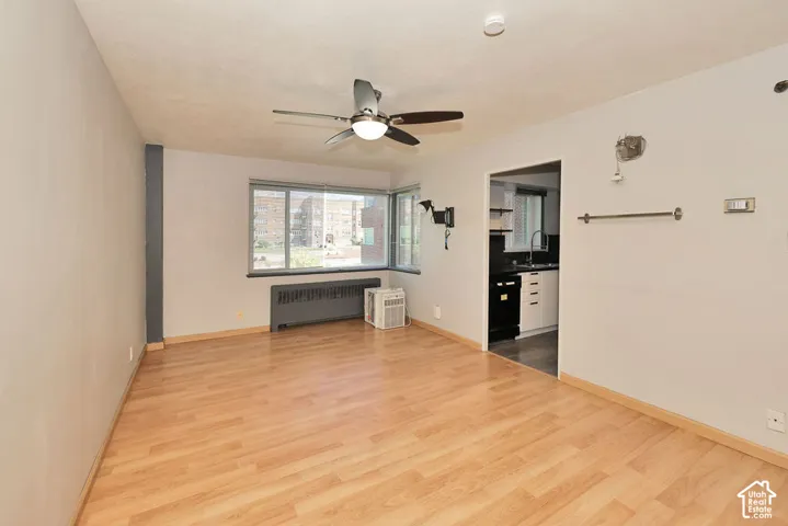 Interior room featuring wood-finish flooring, a ceiling fan with integrated lighting, and multiple windows