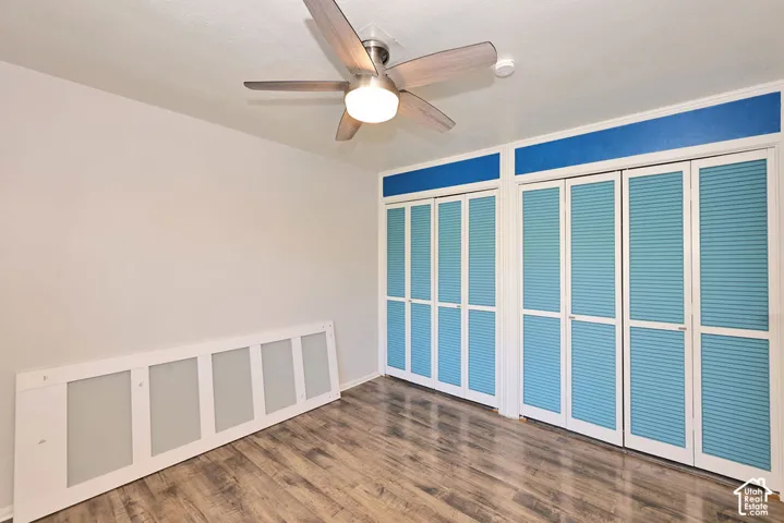 Wood-finish flooring, dual sets of bi-fold louvered closet doors, and a brushed nickel ceiling fan with integrated lighting