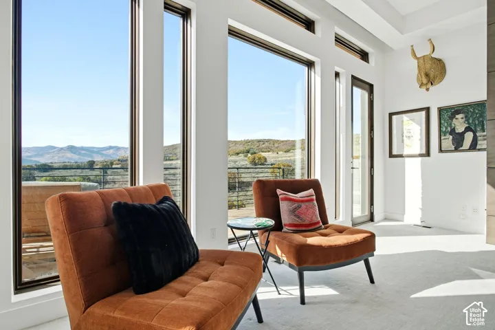 Floor-to-ceiling windows, tray ceiling, and exterior door with glass insert, featuring mountainous horizon scenery