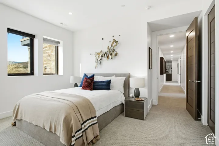 Neutral-toned carpeted flooring, recessed lighting, dual windows with dark frames, and a solid wood-finish interior door
