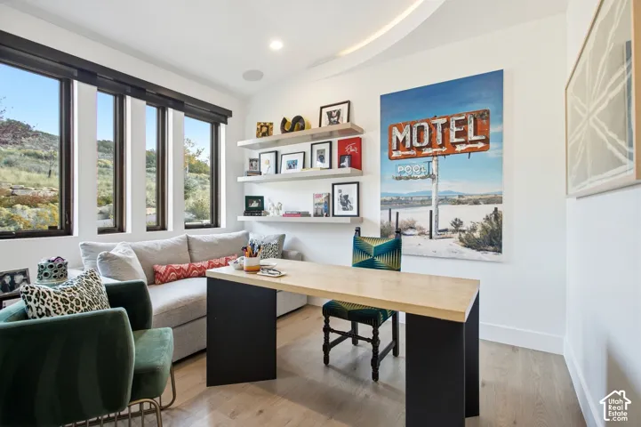Room featuring wood-finish flooring, floor-to-ceiling windows, triple-tier built-in shelving, and recessed ceiling lighting