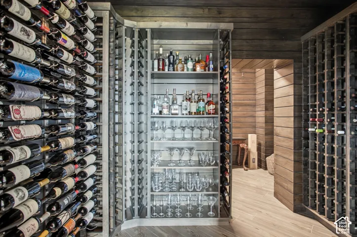 Custom temperature-controlled wine cellar featuring extensive grid-style bottle storage, integrated shelving for glassware, horizontal wood-plank wall paneling, and wood-finish flooring