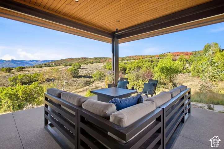 Covered patio featuring a concrete floor, wood-plank ceiling with recessed lighting, and steel structural support, overlooking expansive mountain and natural landscape terrain