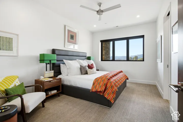 Neutral wall tones, carpeted flooring, multi-pane window with dark frames, recessed lighting, and a modern ceiling fan