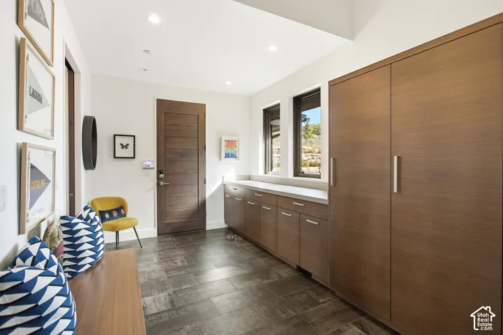 Entryway featuring tile flooring, wood-finish cabinetry, floor-to-ceiling storage, recessed lighting, and a wood-panel door