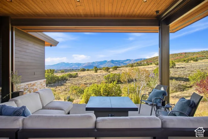Covered patio featuring a wood-plank ceiling, structural steel framing, stone veneer accents, and an open design overlooking expansive natural mountain scenery