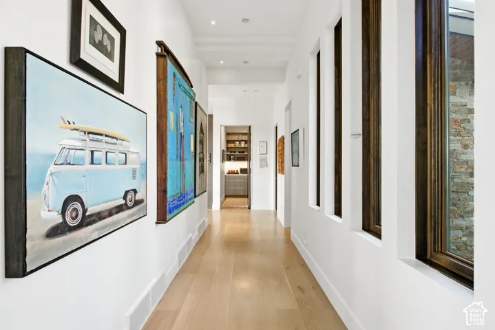 Hallway featuring wood-finish flooring, recessed ceiling lighting, and floor-to-ceiling windows with dark wood trim