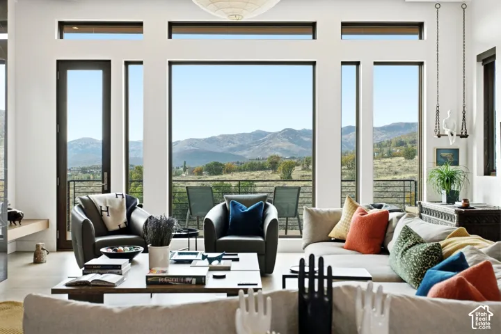 Floor-to-ceiling windows with transom accents, expansive mountain scenery, metal-railed exterior balcony, and pendant lighting