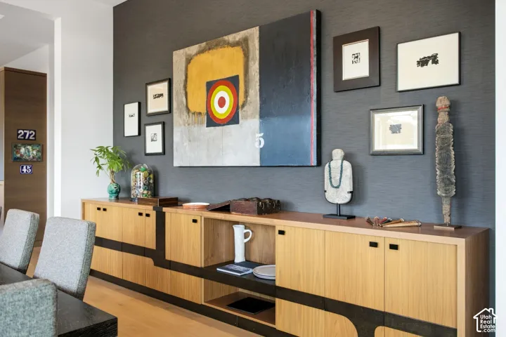 Custom built-in cabinetry featuring light wood finish, integrated dark accent detailing, and open shelving, set against a dark textured accent wall