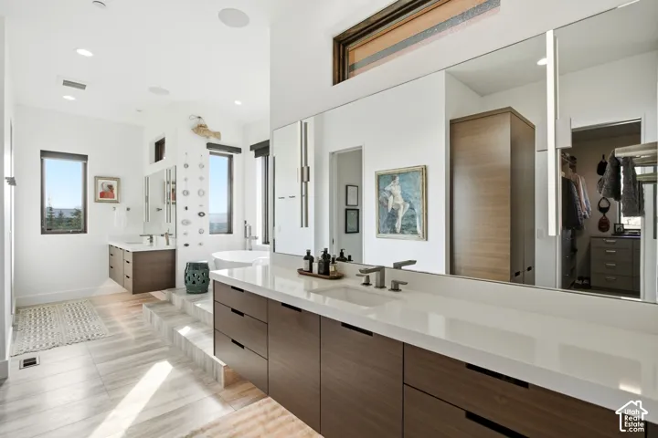 Floating wood-finish cabinetry with white quartz countertops, integrated rectangular sinks, polished nickel fixtures, and full-wall mirrors with vertical integrated lighting