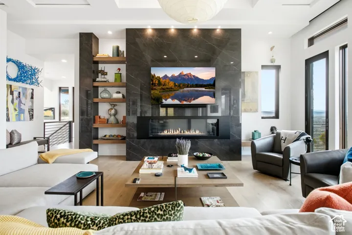 Floor-to-ceiling stone fireplace surround with a linear hearth, integrated wood-finish shelving, coffered ceiling, and wood-finish flooring