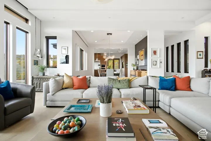 Open-concept interior featuring wood-finish flooring, floor-to-ceiling windows, recessed lighting, and a multi-pendant chandelier