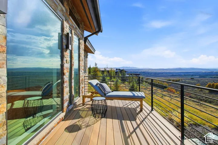 Elevated deck featuring composite decking, horizontal cable railing, full-height exterior stone cladding, and floor-to-ceiling glass windows