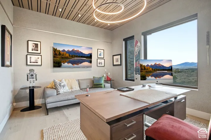 Custom room featuring wood-slat ceiling, modern circular light fixture, wood-finish flooring, and large windows with mountain scenery