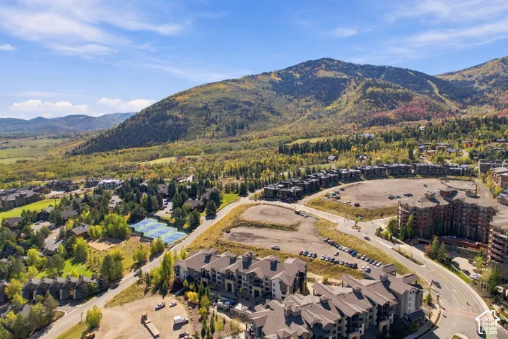 Aerial perspective featuring multi-story residential architecture, surrounding mountain terrain, and proximity to tennis courts