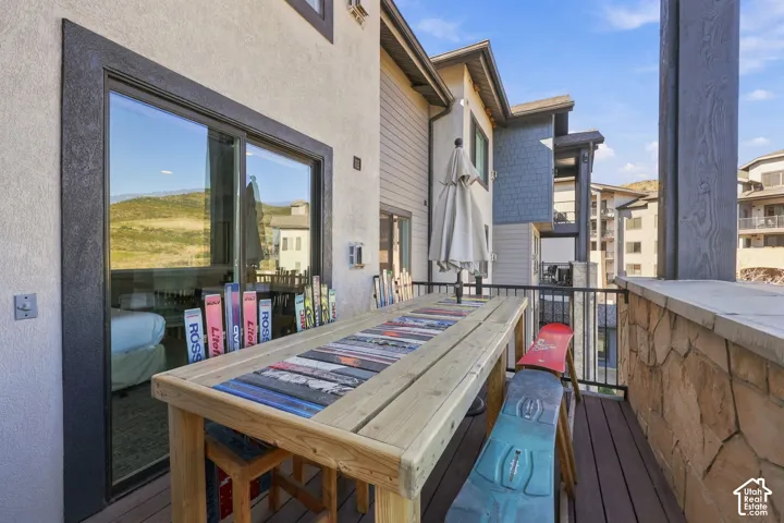 Private deck featuring wood-finish decking, stone masonry accents, metal railing, and sliding glass door entry