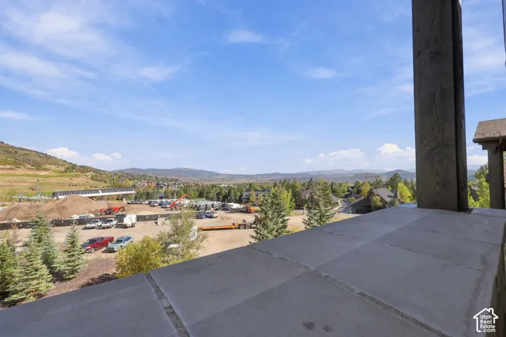 Elevated outdoor terrace featuring stone flooring, a heavy timber support post, and mountain scenery