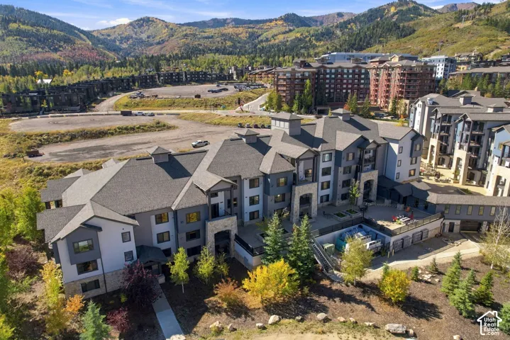 Multi-story exterior featuring stone veneer accents, multi-gabled rooflines, timber framing details, and paved patio space, set against a mountainous backdrop