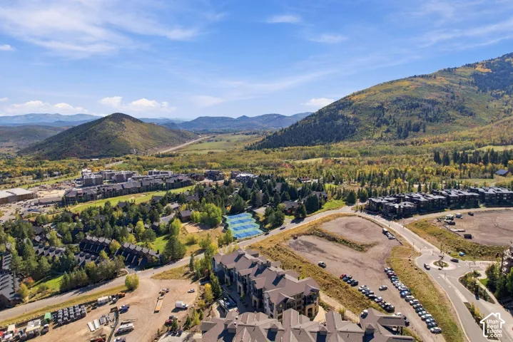 Aerial perspective featuring expansive mountain topography, dense evergreen forestation, and paved roadways, set against a backdrop of sweeping rolling hills