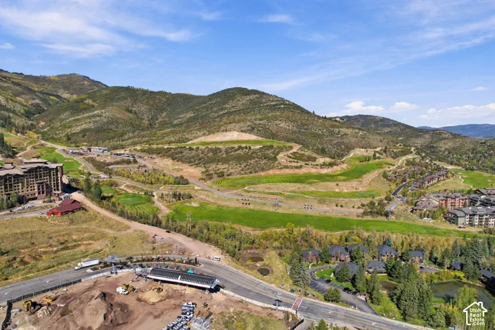 Aerial perspective of mountainous terrain featuring rolling slopes, vast green space, and paved roadways