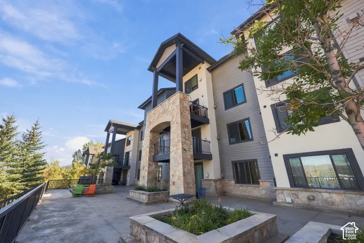 Multi-story exterior featuring stone veneer accents, lap siding, private recessed balconies with metal railings, and integrated concrete planters
