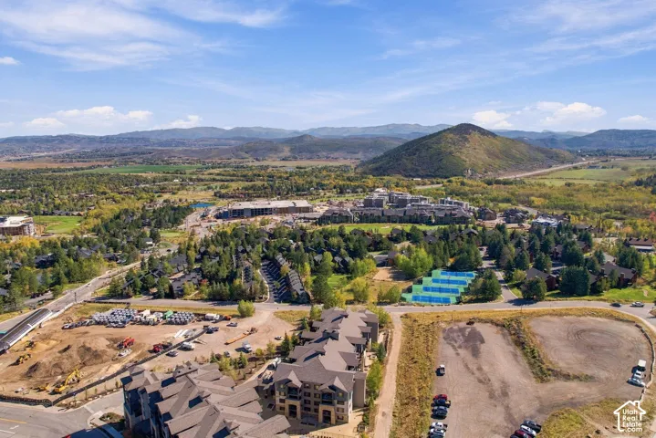 Aerial perspective featuring multi-story residential structures, a complex of tennis courts, and expansive mountain scenery