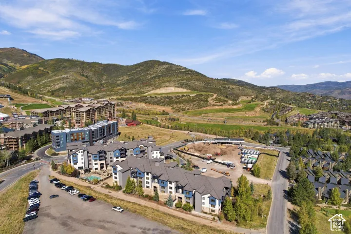 Multi-story residential complex featuring stone and siding exterior, multi-pitched rooflines, integrated swimming pool, and expansive mountain backdrop