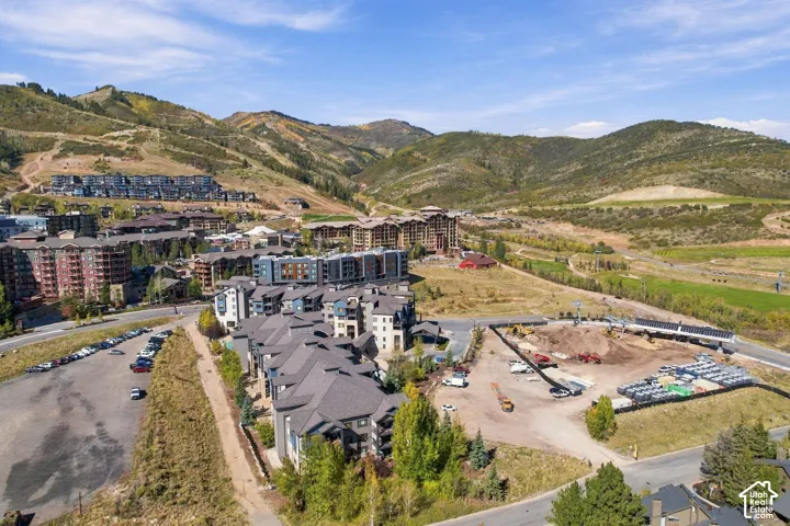 Aerial perspective featuring a multi-story residential complex with shingled roofing, set against a mountainous landscape with surrounding natural terrain