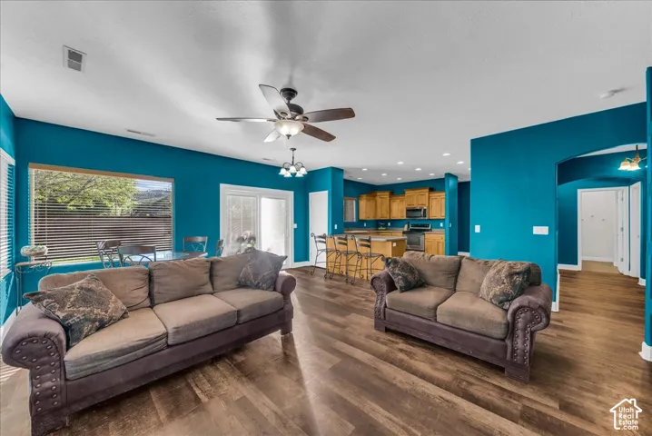 Open-concept space featuring wood-finish flooring, a kitchen island, recessed lighting, a ceiling fan, and sliding glass doors