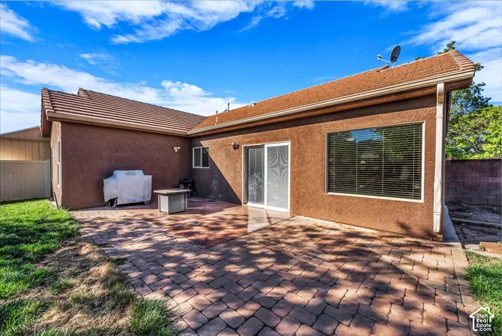 Rear exterior featuring stucco siding, a tiled roof, a paved patio, and sliding glass doors